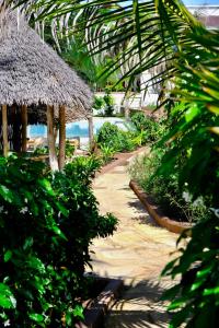 a path leading to a beach with a thatch umbrella at Nyumbani Residence Apartments in Jambiani