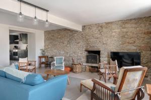 a living room with a blue couch and a stone wall at Charmante maison proche de l'océan pour 8 personnes in Penvins
