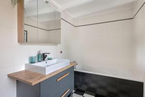 a bathroom with a white sink and a bath tub at Charmante maison proche de l'océan pour 8 personnes in Penvins +13 photos