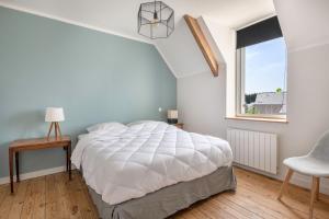 a bedroom with a large white bed and a window at Charmante maison proche de l'océan pour 8 personnes in Penvins