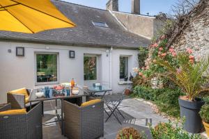 a patio with a table and a yellow umbrella at Charmante maison proche de l'océan pour 8 personnes in Penvins