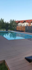 a large swimming pool with a wooden deck at Apartament na Piaskowej in Żarnowska