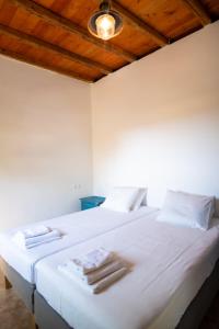 Un dormitorio con una cama blanca con toallas. en Simboro house - Kythoikies holiday houses en Kýthira