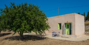 a house with two chairs and a tree in front of it at Simboro house - Kythoikies holiday houses in Kýthira