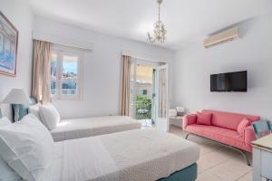 a white bedroom with two beds and a red couch at Arolithos in Spetses