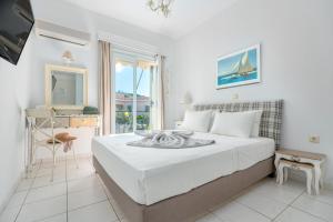 a white bedroom with a bed and a window at Arolithos in Spetses