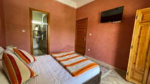 a bedroom with a bed and a television on a wall at DAR TAWJA in Asguine