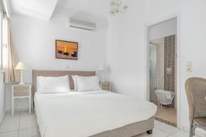 a white bedroom with a bed and a bathroom at Arolithos in Spetses