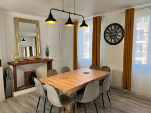een eettafel met stoelen en een klok aan de muur bij Homefleur - Maison 130m2 - 8 à 10 pers - Jardin in Honfleur