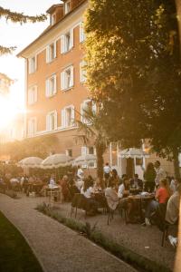 a group of people sitting at tables in front of a building at Parkhotel Mondschein, a Member of Design Hotels in Bolzano