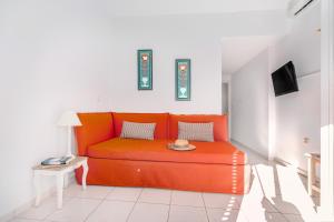 an orange couch in a living room with a table at Arolithos in Spetses
