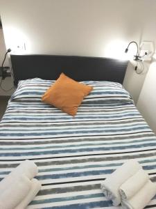 een bed met een oranje kussen en twee handdoeken erop bij Theatron Houses- Centro Storico in Catania +59 foto's