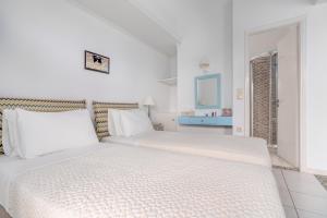a white bedroom with two beds with white pillows at Arolithos in Spetses