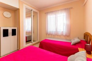 two beds in a room with pink sheets at MI PERLA in Torrevieja