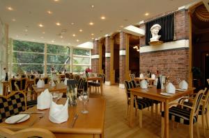 a restaurant with wooden tables and chairs and windows at Liverpool Aigburth Hotel, Sure Hotel Collection by BW in Liverpool