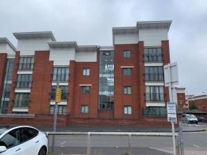 a white car parked in front of a brick building at 2 Bedroom 2 Bath Apartment, sleeps 4, Town Centre in Wolverhampton