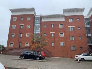 two cars parked in front of a brick building at 2 Bedroom 2 Bath Apartment, sleeps 4, Town Centre in Wolverhampton