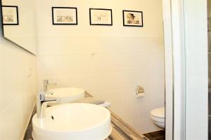 a white bathroom with a sink and a toilet at Haus Wiekend - Fewo Knurrhahn in Wiek auf Rügen  +2 photos