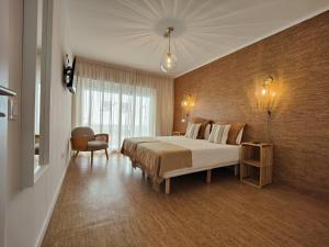 um quarto de hotel com uma cama e uma cadeira em Corkoon Boutique Studios & Apartments - Duna Parque Group em Vila Nova de Milfontes