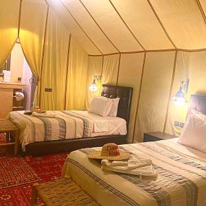 a room with two beds in a tent at Desert Heart Luxury Camp in Merzouga