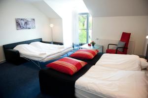 a bedroom with two beds with red pillows on them at Vejlsøhus Hotel and Conference Center in Silkeborg