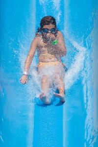 a girl in a swimsuit riding a wave in a pool at Atlas Amadil Beach Hotel in Agadir