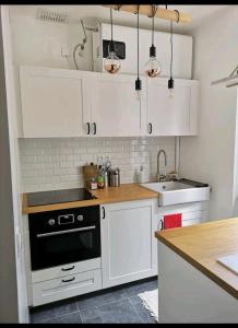 una cocina con armarios blancos y horno negro en Happy Place - 15 min Paris & 30 min DisneyLand - Subways - Facilities - Free parking - Secured en Maisons-Alfort