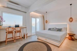 a bedroom with a bed and a desk with a table at Nautica Suites - Modern Seaview Suite in Antiparos