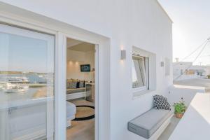 Habitación blanca con ventana y silla blanca en Nautica Suites - Modern Seaview Suite, en Antíparos