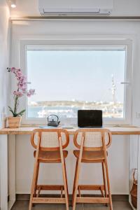 a desk with two chairs in front of a window at Nautica Suites - Modern Seaview Suite in Antiparos Town