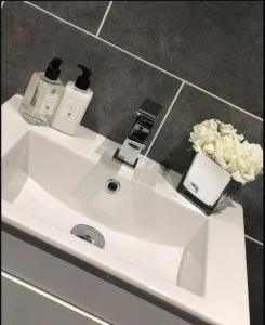 a bathroom sink with two bottles and a vase of flowers at Chester City Apartments - With free parking in Chester