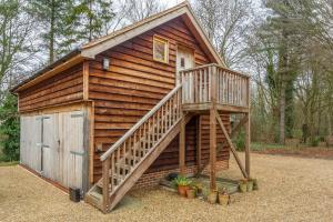 a large wooden cabin with a stairs leading up to it at Woodland Retreat Lodge in Brundish