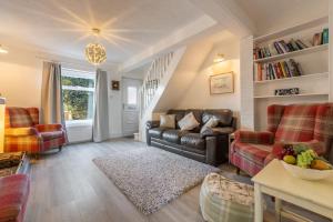 a living room with a leather couch and chairs at Hideaway Cottage in Leiston