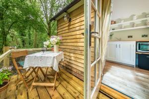 a patio with a table on a wooden deck at Woodland Retreat Shepherd's Hut in Brundish