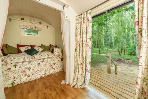 a bedroom with a bed and a large window at Woodland Retreat Shepherd's Hut in Brundish