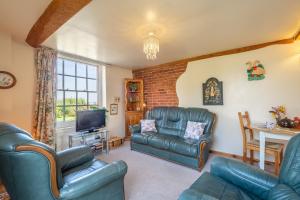 a living room with leather furniture and a tv at Honeypot Cottage in Ipswich