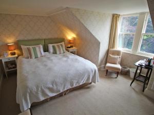 a bedroom with a large white bed and a chair at Viewfield House in Portree