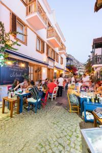 un grupo de personas sentadas en las mesas fuera de un restaurante en Kalkan Han Hotel, en Kalkan