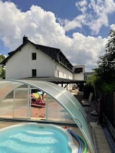 a swimming pool with a bridge and a house at Penzion Alfa in Železná Ruda