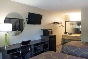 a hotel room with a bed and a desk and a mirror at Super 8 by Wyndham Brownsburg in Brownsburg