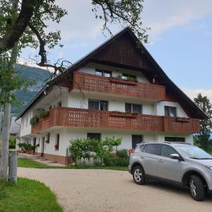a house with a car parked in front of it at Apartmaji Pri Medvedu in Bohinj