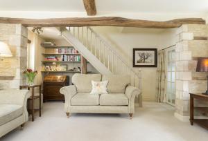 a living room with a chair and a staircase at Hope Cottage in Quenington
