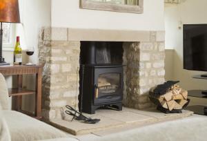 a brick fireplace with a stove in a living room at Hope Cottage in Quenington