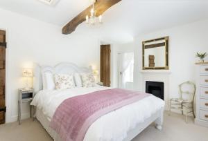 a white bedroom with a white bed and a mirror at Hope Cottage in Quenington