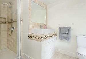 a white bathroom with a sink and a shower at Hope Cottage in Quenington +24 photos