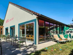 een gebouw met stoelen en tafels erbuiten bij Greet Hotel Versailles - Voisins Le Bretonneux in Voisins-le-Bretonneux