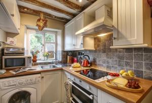 cocina con armarios blancos y lavavajillas en Bay Tree Cottage, en Shipton under Wychwood