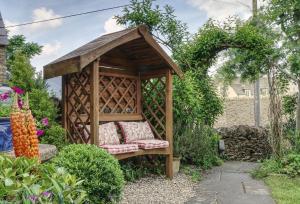 a wooden gazebo with a bench in a garden at Bay Tree Cottage in Shipton under Wychwood
