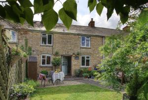 une maison en briques avec une table dans la cour dans l'établissement Bay Tree Cottage, à Shipton under Wychwood 11 autres photos