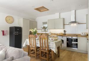 Una cocina y un comedor con mesa y sillas. en Grooms Cottage, en Kingham